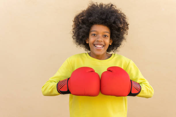 pre adolescent boy with boxing red gloves on beige background