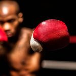 young woman boxer holding up red boxing gloves ready to box in a boxing ring.
