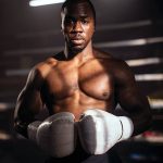 athletic boxer stands in gym lighting wearing white gloves, ready for training